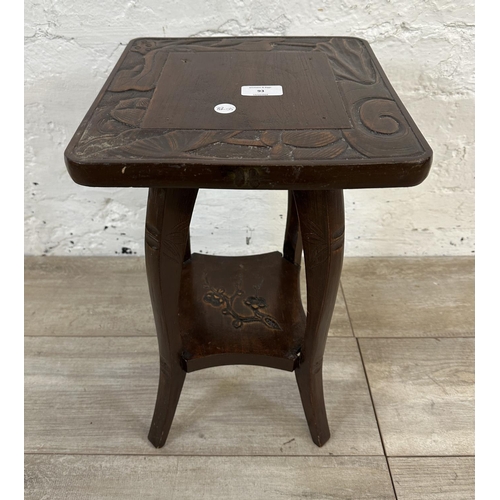 93 - An Arts and Crafts style carved hardwood two tier side table in the manner of Liberty & Co - approx.... 