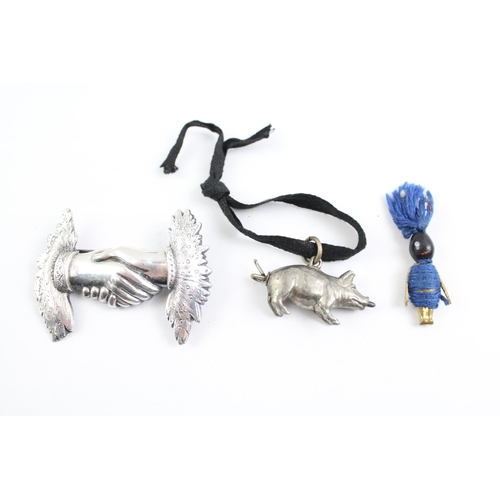 2115 - Three pieces of jewellery, one Touch Wud charm, one white metal hand brooch and one white metal pig ... 