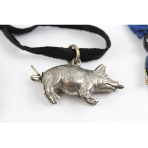 2115 - Three pieces of jewellery, one Touch Wud charm, one white metal hand brooch and one white metal pig ... 