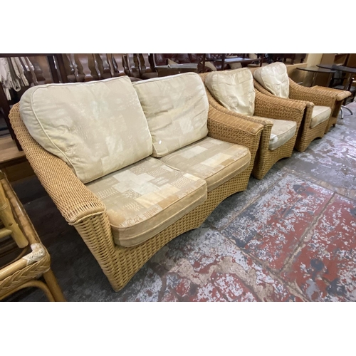 62 - A wicker four piece conservatory suite comprising two seater sofa, two armchairs and side table