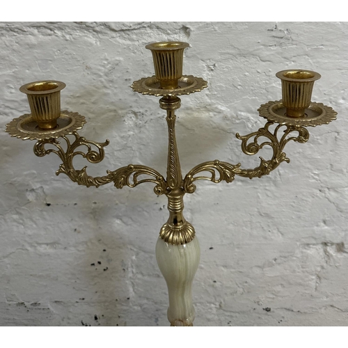 16 - Four onyx and gilt metal items, three candelabras and one floor standing ashtray - approx. 64cm high