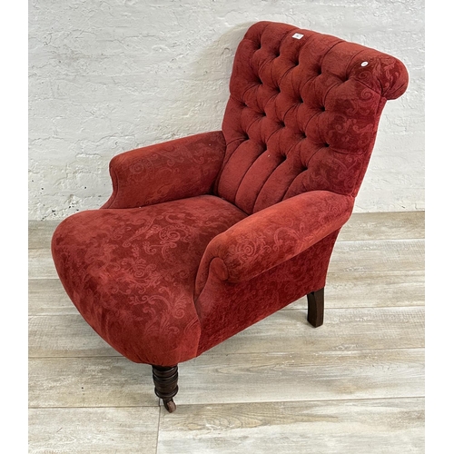 180 - A Victorian red fabric button back upholstered armchair on mahogany supports and castors - approx. 9... 