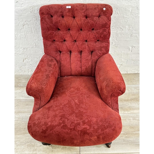 180 - A Victorian red fabric button back upholstered armchair on mahogany supports and castors - approx. 9... 