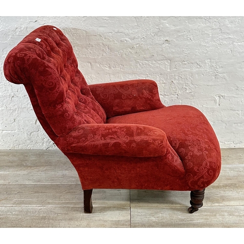 180 - A Victorian red fabric button back upholstered armchair on mahogany supports and castors - approx. 9... 