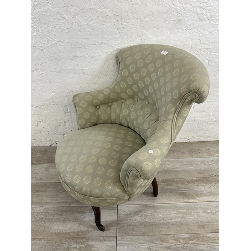 65 - A Victorian button back fabric upholstered armchair on mahogany supports and castors