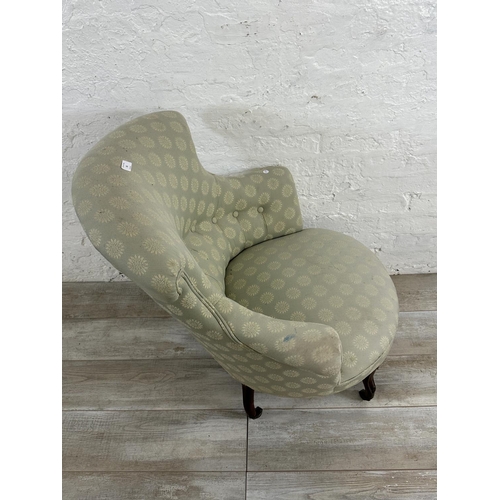 65 - A Victorian button back fabric upholstered armchair on mahogany supports and castors