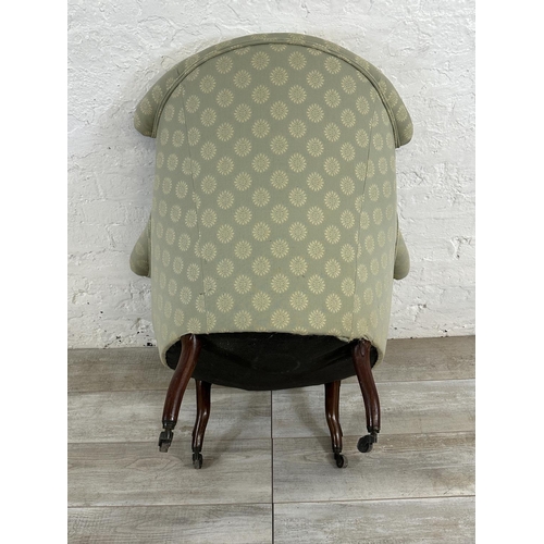 65 - A Victorian button back fabric upholstered armchair on mahogany supports and castors