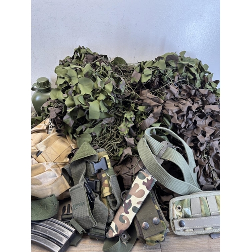 410 - A collection of military and paintballing clothing and accessories to include green canvas ammunitio... 