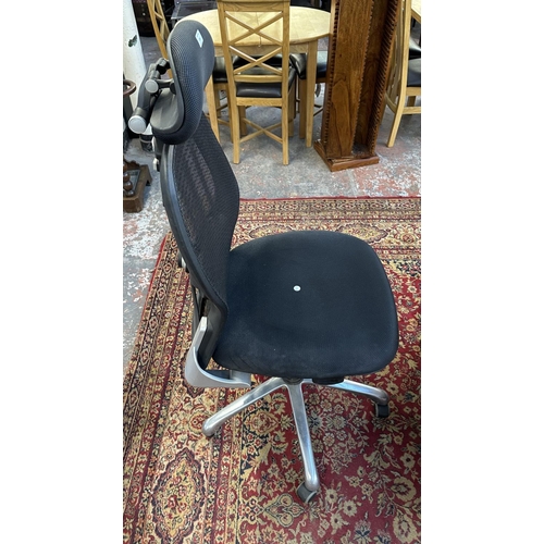 1147 - A modern black plastic and meshed fabric swivel office desk chair