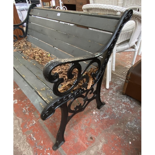 1134 - A cast iron and wooden slatted garden bench - approx. 77cm high x 126cm wide x 60cm deep