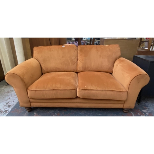 1164 - A modern orange fabric upholstered two seater sofa on turned wood supports - approx. 72cm high x 180... 