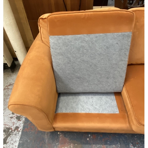 1164 - A modern orange fabric upholstered two seater sofa on turned wood supports - approx. 72cm high x 180... 