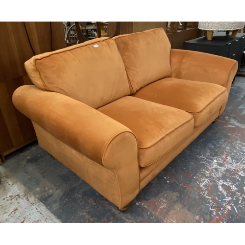 1164 - A modern orange fabric upholstered two seater sofa on turned wood supports - approx. 72cm high x 180... 