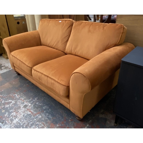 1164 - A modern orange fabric upholstered two seater sofa on turned wood supports - approx. 72cm high x 180... 