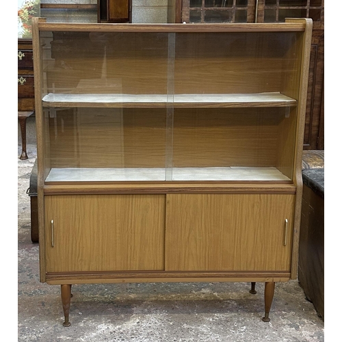 67 - A mid 20th century teak effect bookcase with two glass sliding doors - approx. 109cm high x 91cm wid... 