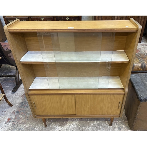 67 - A mid 20th century teak effect bookcase with two glass sliding doors - approx. 109cm high x 91cm wid... 