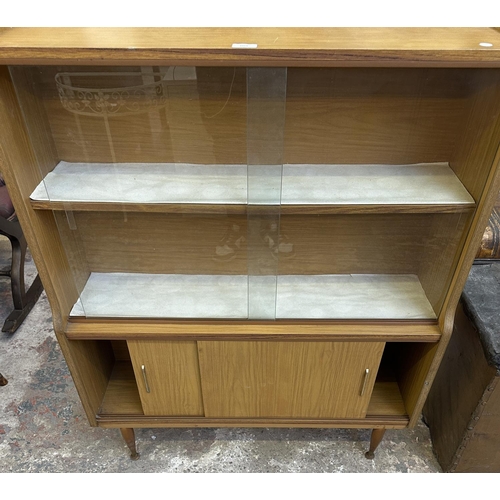 67 - A mid 20th century teak effect bookcase with two glass sliding doors - approx. 109cm high x 91cm wid... 