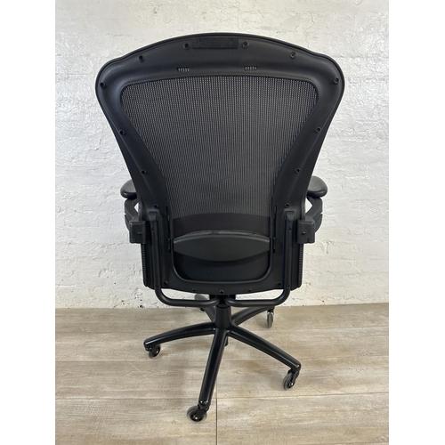 100 - A modern black plastic and meshed swivel office desk chair