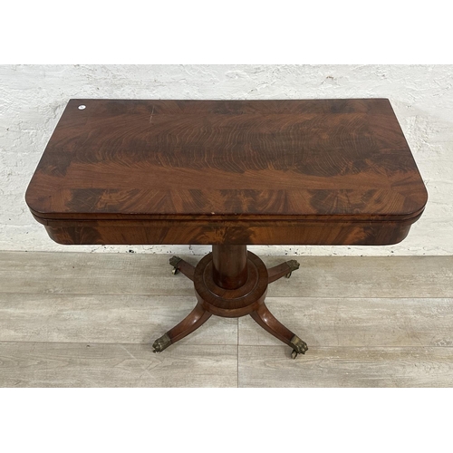 11 - A 19th century mahogany fold over games table with green baize interior and brass lion paw supports ... 