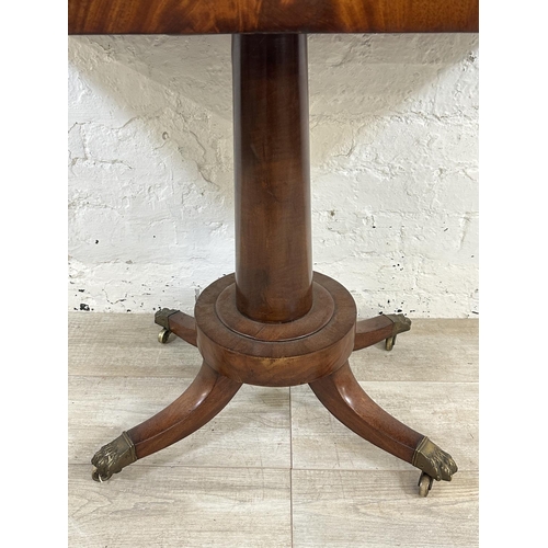 11 - A 19th century mahogany fold over games table with green baize interior and brass lion paw supports ... 