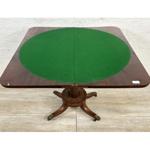 11 - A 19th century mahogany fold over games table with green baize interior and brass lion paw supports ... 