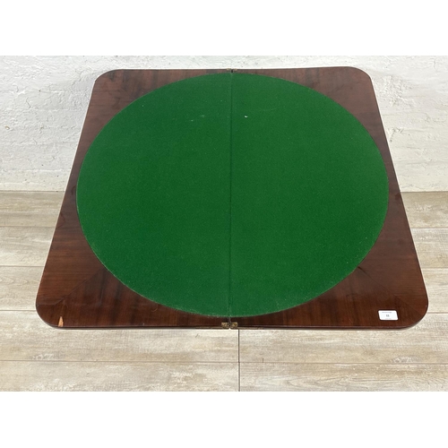 11 - A 19th century mahogany fold over games table with green baize interior and brass lion paw supports ... 