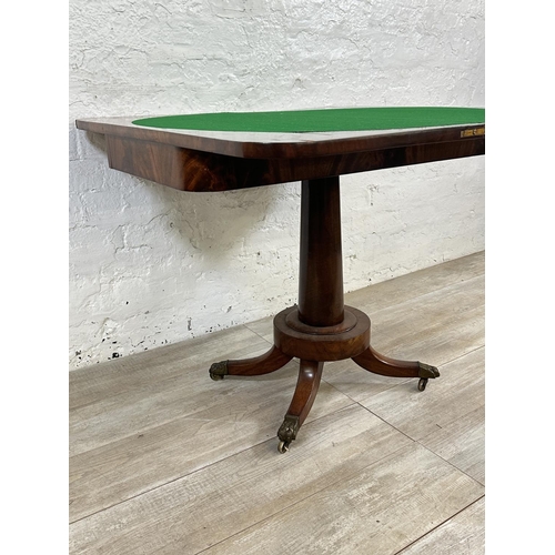 11 - A 19th century mahogany fold over games table with green baize interior and brass lion paw supports ... 