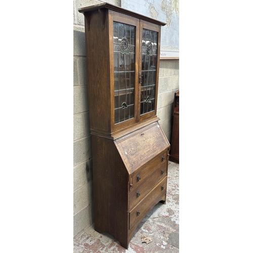 43 - An early 20th century oak bureau bookcase with two stained and lead glazed doors - approx. 194cm hig... 