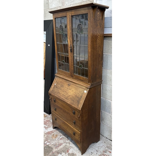 43 - An early 20th century oak bureau bookcase with two stained and lead glazed doors - approx. 194cm hig... 