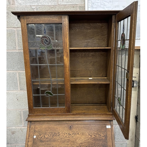 43 - An early 20th century oak bureau bookcase with two stained and lead glazed doors - approx. 194cm hig... 