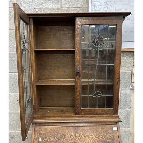 43 - An early 20th century oak bureau bookcase with two stained and lead glazed doors - approx. 194cm hig... 