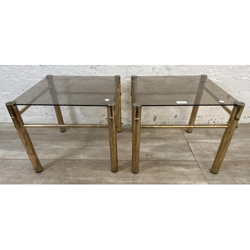 134 - A pair of Hollywood Regency style brass and smoked glass side tables - approx. 37cm high x 42cm wide... 