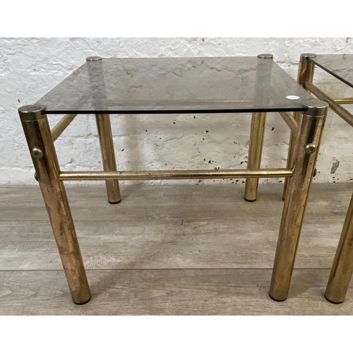 134 - A pair of Hollywood Regency style brass and smoked glass side tables - approx. 37cm high x 42cm wide... 