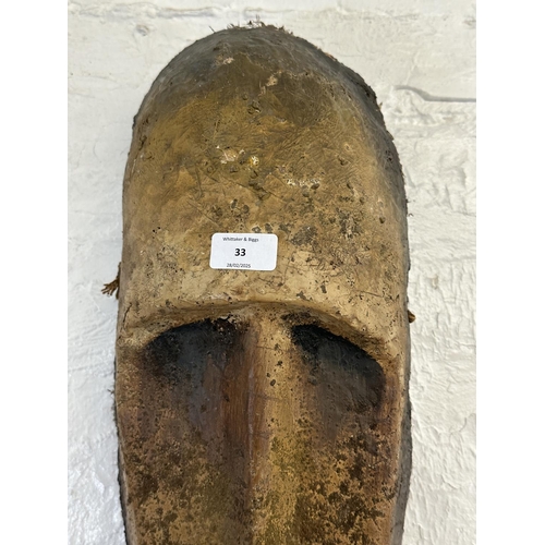 33 - A fibreglass African tribal wall hanging mask - approx. 65cm high