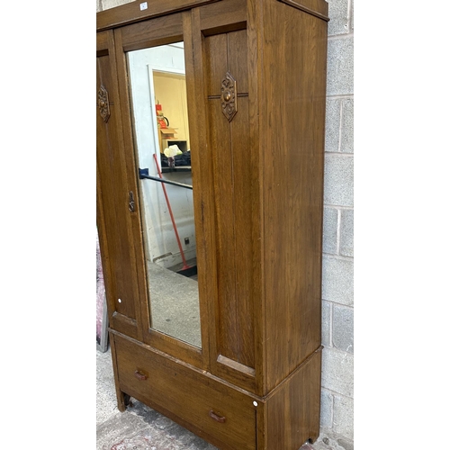 67 - An early 20th century carved oak mirror door wardrobe - approx. 196cm high x 100cm wide x 47cm deep