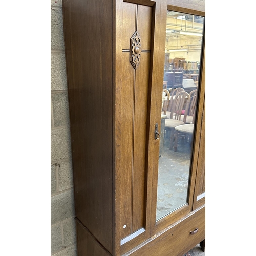 67 - An early 20th century carved oak mirror door wardrobe - approx. 196cm high x 100cm wide x 47cm deep