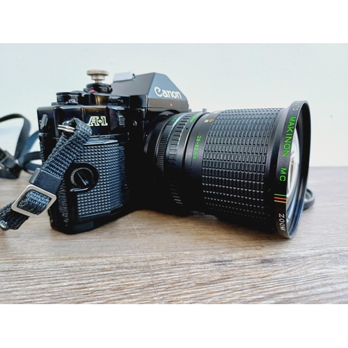 949 - Two Canon A-1 35mm SLR cameras, one fitted with Makinon MC 1:3.5-4.5 28-80mm auto zoom lens and one ... 