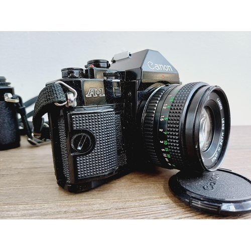 953 - Two Canon 35mm SLR cameras, one A-1 fitted with FD 1:1.8 50mm lens and one AV-1 body