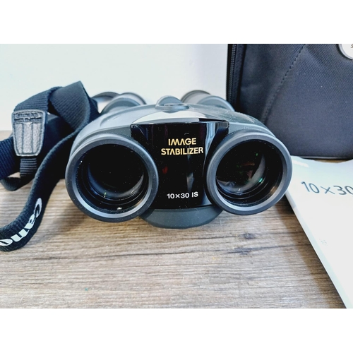 1077 - A cased pair of Canon 10x30 IS Image Stabilizer binoculars with instruction manual