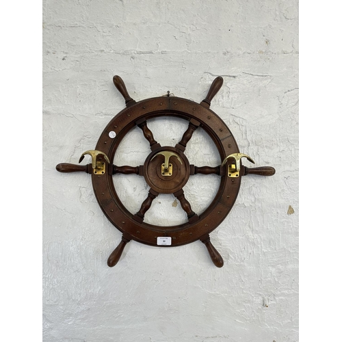 30 - A carved hardwood and brass novelty ships wheel coat rack - approx. 55cm diameter