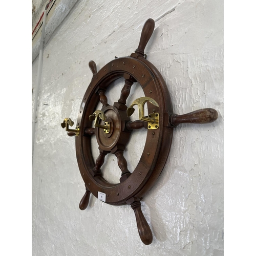 30 - A carved hardwood and brass novelty ships wheel coat rack - approx. 55cm diameter