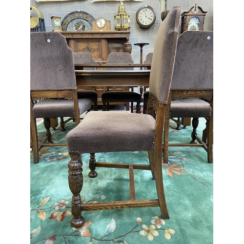 52 - A mid 20th century Jacobean style carved oak wind out dining table and six chairs with extension lea... 