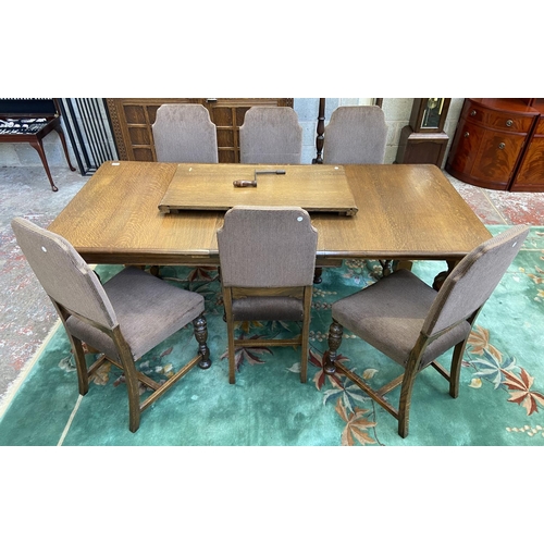 52 - A mid 20th century Jacobean style carved oak wind out dining table and six chairs with extension lea... 