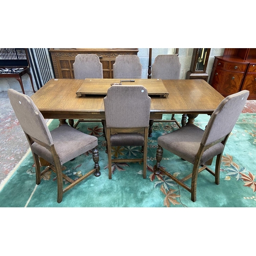 52 - A mid 20th century Jacobean style carved oak wind out dining table and six chairs with extension lea... 