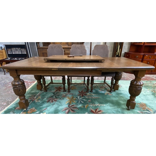 52 - A mid 20th century Jacobean style carved oak wind out dining table and six chairs with extension lea... 