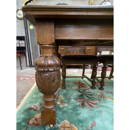 52 - A mid 20th century Jacobean style carved oak wind out dining table and six chairs with extension lea... 