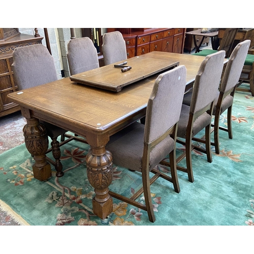 52 - A mid 20th century Jacobean style carved oak wind out dining table and six chairs with extension lea... 