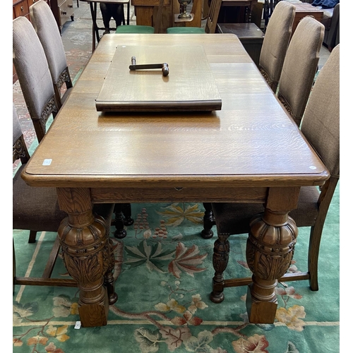 52 - A mid 20th century Jacobean style carved oak wind out dining table and six chairs with extension lea... 