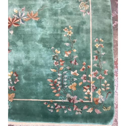 54 - A mid/late 20th century Chinese machine woven green ground floral pattern rug - approx. 395cm x 304c... 