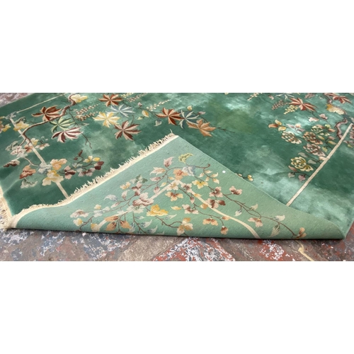 54 - A mid/late 20th century Chinese machine woven green ground floral pattern rug - approx. 395cm x 304c... 